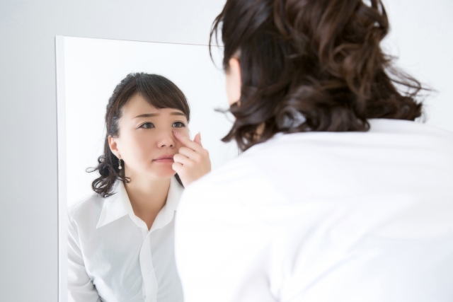 鏡で目元を見ている女性