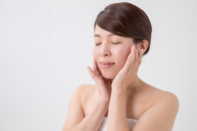 目を閉じて頬を触る女性